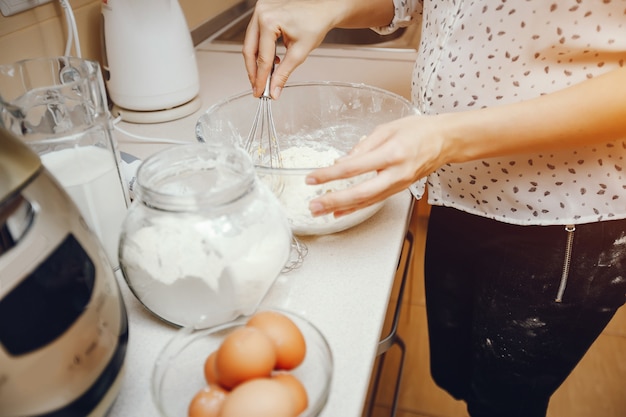흰 셔츠에 젊은 여자가 부엌에서 집에서 음식을 준비하고있다