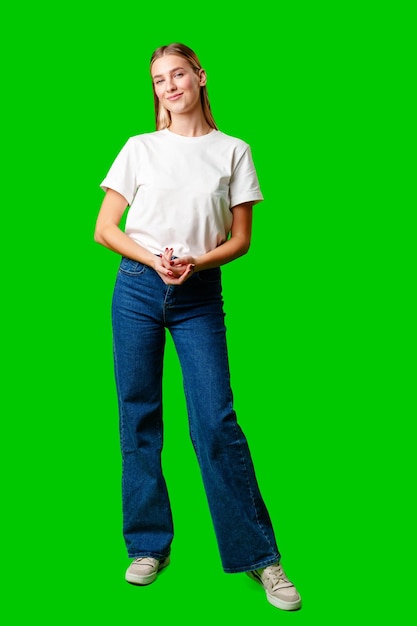 白いシャツを着た若い女性が緑の背景に写真を撮っている