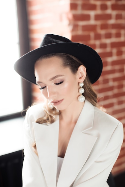 Young woman in a white suit and a black hat