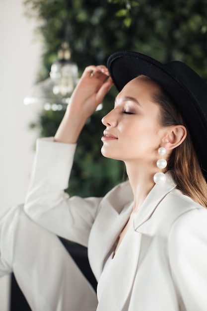 Foto giovane donna in un abito bianco e un cappello nero