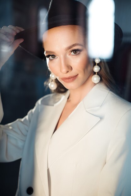 Young woman in a white suit and a black hat