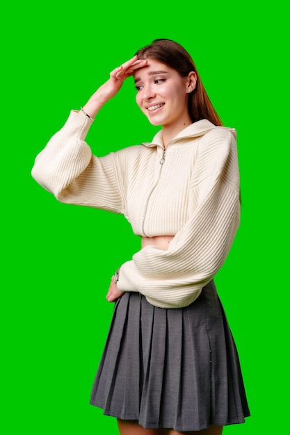 Young woman in white sweater and grey skirt smiling against green background