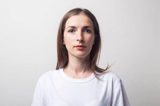 Young woman in a white T-shirt on a light background.