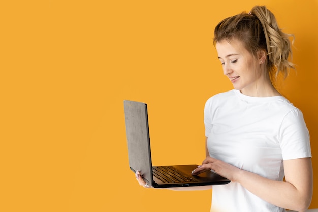 Young woman in a white t-shirt using a laptop