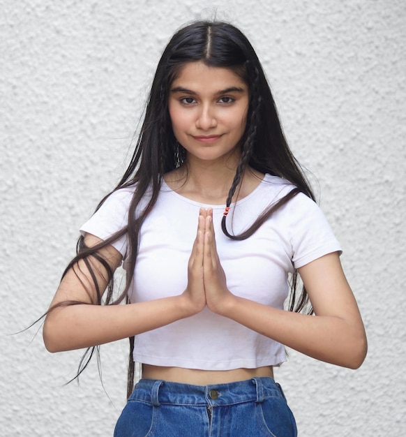 A young woman in a white top is doing a yoga pose.