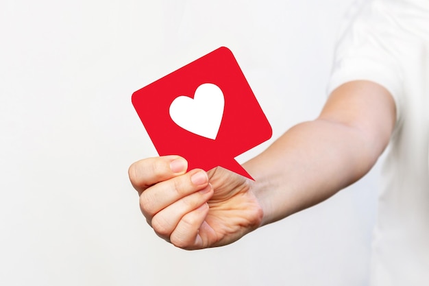 Young woman in a white tshirt holding a big like symbol from social media in her hand