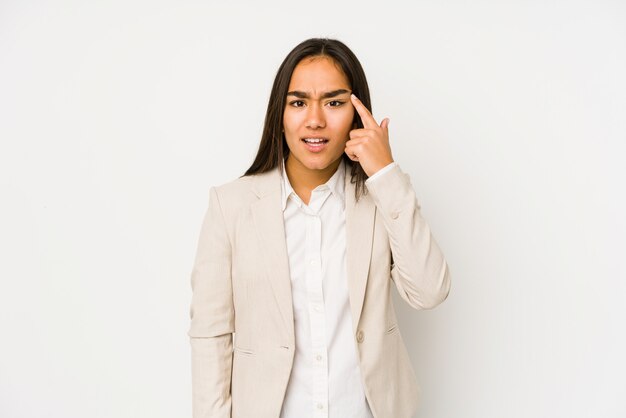 Young woman on a white wall showing a disappointment gesture with forefinger.