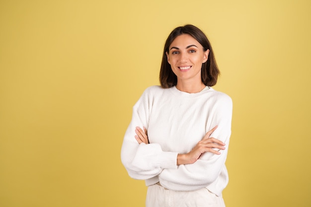 Young woman in white warm sweater smiling with arms crossed