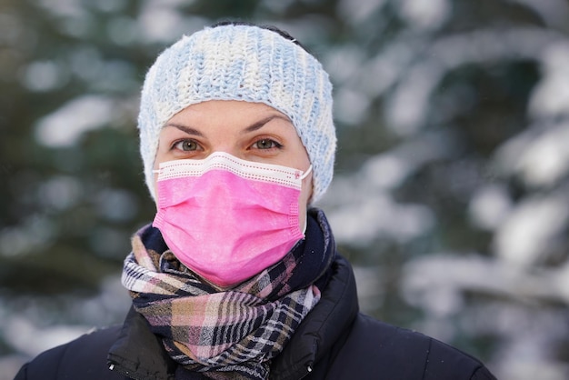 Young woman in winter jacket with pink disposable single use face virus mask