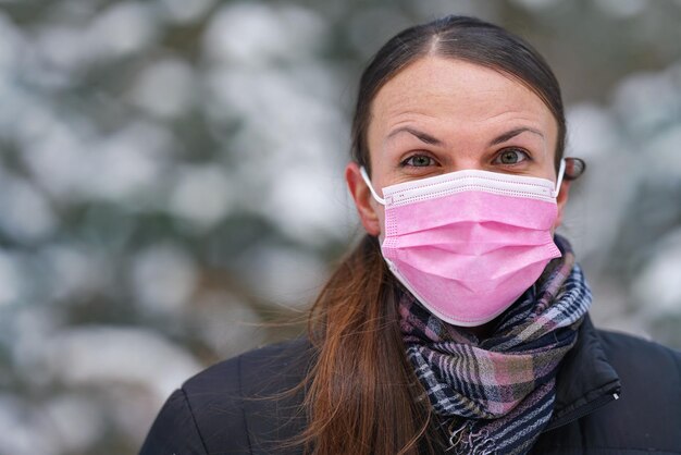 Young woman in winter jacket with pink disposable single use face virus mask