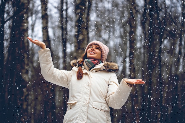 降雪の冬の公園で若い女性