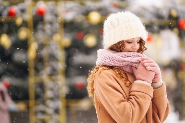 Young woman in winter style clothes posing at festive street\
market cold weather winter fashion