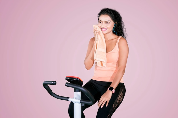 Young woman wipes her sweat on an exercise bike