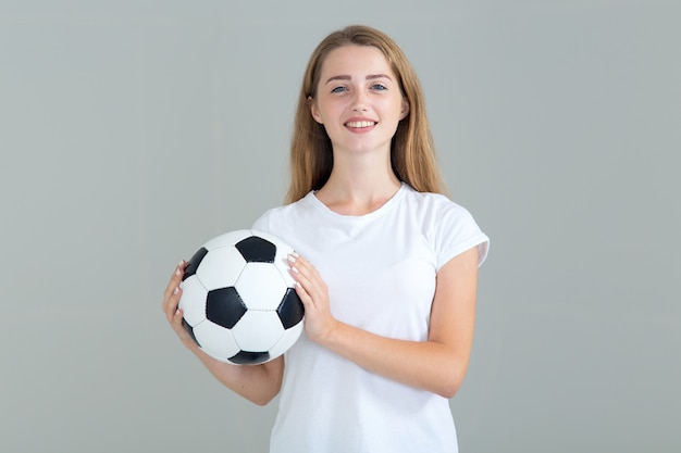 사진 회색에 고립 된 그녀의 손에 축구 공을 가진 젊은 여자