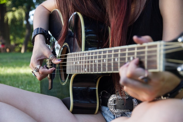 Young woman with an acoustic guitar in the park