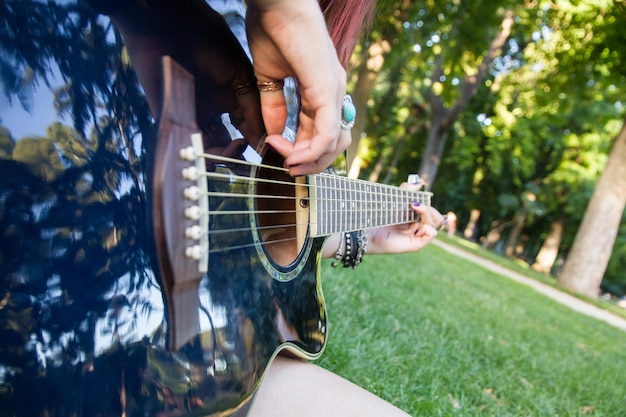 Foto giovane donna con una chitarra acustica nel parco