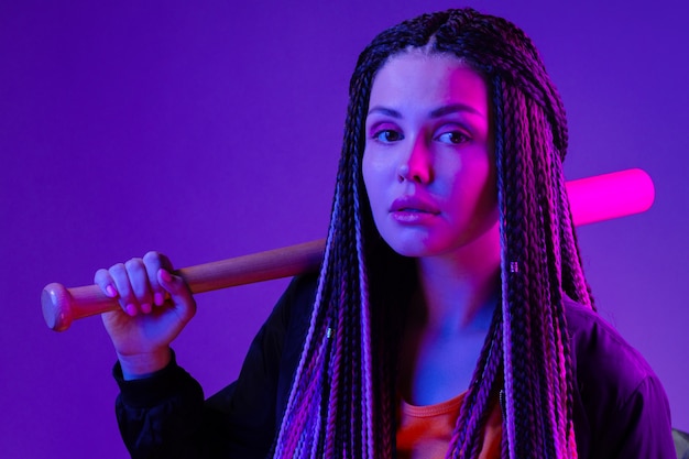 Young woman with afro braids holding a bit on a shoulder in neon lught