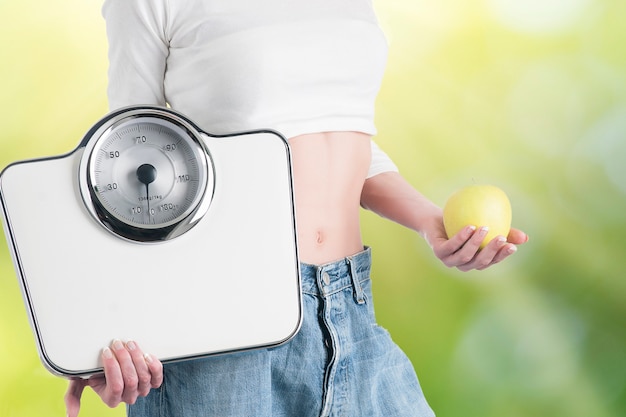 Photo young woman with apple and scales. healthy diet and weight loss