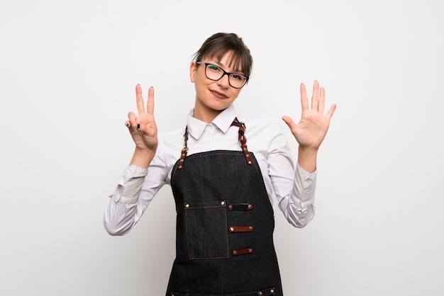 Young woman with apron counting seven with fingers