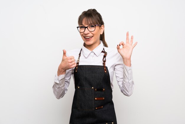 Young woman with apron showing ok sign and thumb up gesture