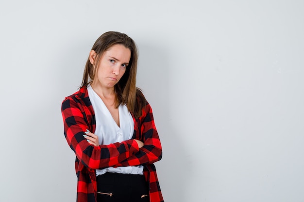 Young woman with arms folded in casual clothes and looking dismal. front view.