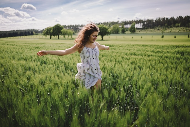 Foto giovane donna con le braccia tese in piedi su un paesaggio erboso.