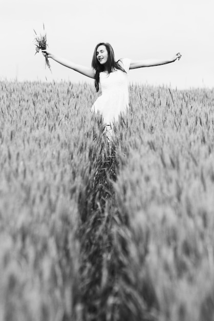 young woman with arms outstretched standing at wheat farm
