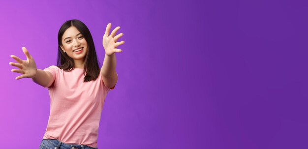 Young woman with arms raised against blue background