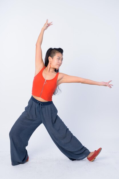 Young woman with arms raised against white background