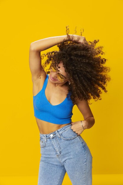 Young woman with arms raised against yellow background