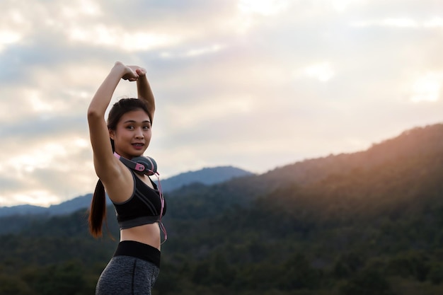 写真 夕暮れの時腕を上げて空に向かって立っている若い女性