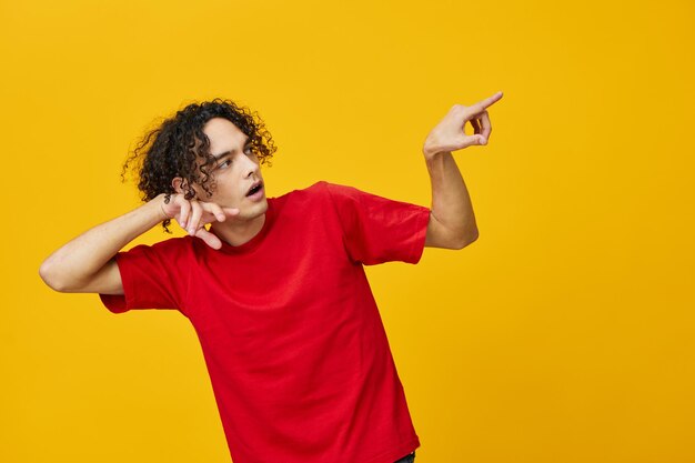 Young woman with arms raised standing against yellow background