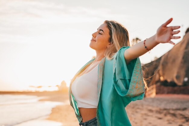 Young woman with arms raised standing at beach