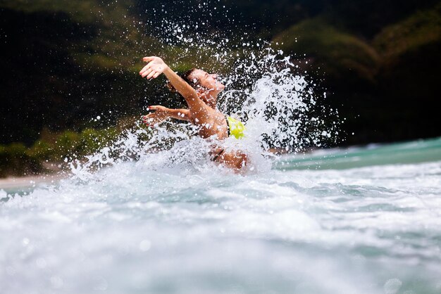 写真 腕を上げて海で泳ぐ若い女性