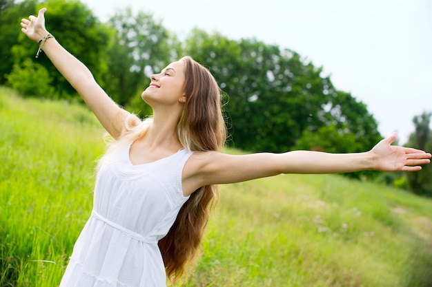 young woman with arms wide open in a field