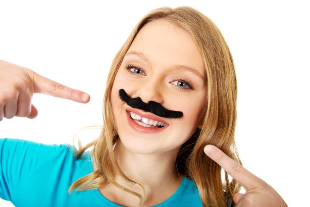 Young woman with artificial mustache against white background