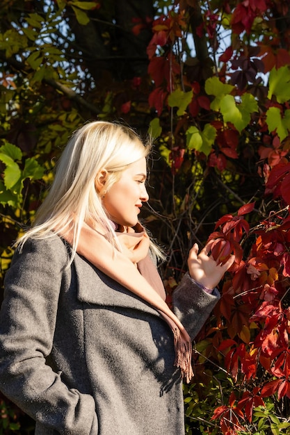 Young woman with autumn leaves in hand and fall yellow maple garden background.