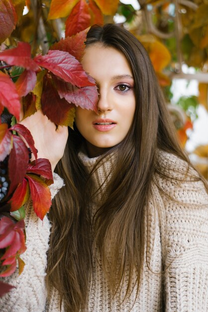 Giovane donna con foglie di autunno in mano