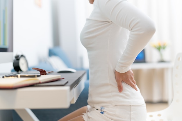 Young woman with back pain working with computer healthcare and medical concept