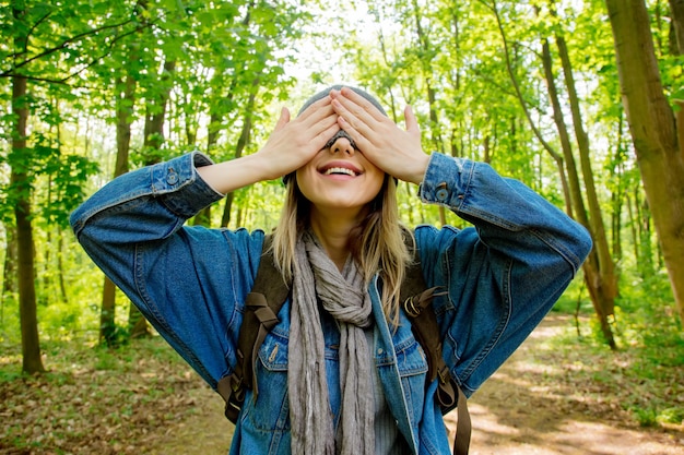 Giovane donna con zaino nasconde il viso con una sciarpa in una foresta mista beskidy in polonia in primavera.