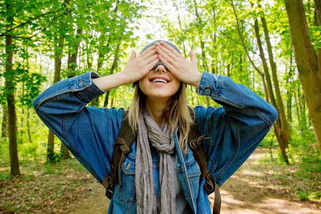 Young woman with backpack hide face with a scarf in a mixed forest Beskidy in Poland in spring time.