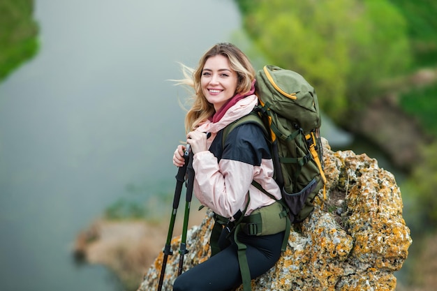 写真 バックパックを背負った若い女性が山をハイキング ハイキングコンセプト トレッキング崖 旅行旅行者