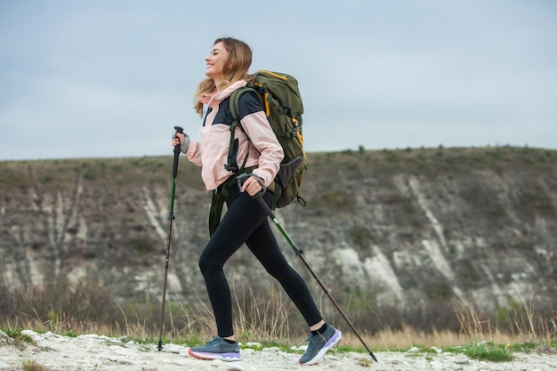 バックパックを背負った若い女性が山をハイキング ハイキングコンセプト トレッキング崖 旅行旅行者
