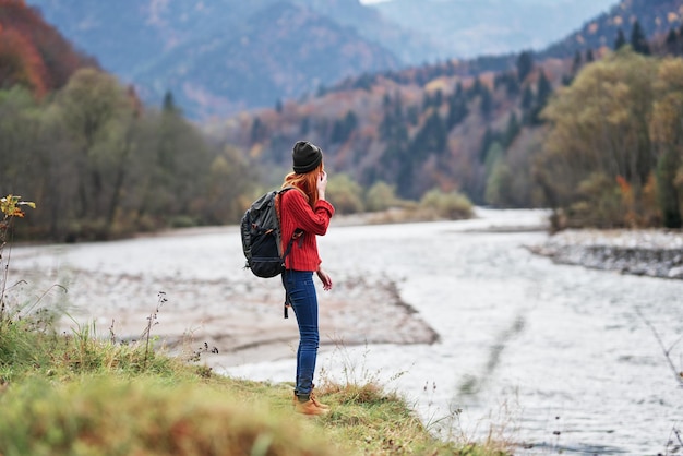 Young woman with backpack in the mountains autumn travel tourism landscape shallow water river