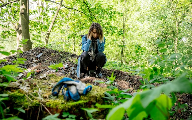 Young woman with backpack near garbage in a mixed forest Beskidy in Poland in spring time.