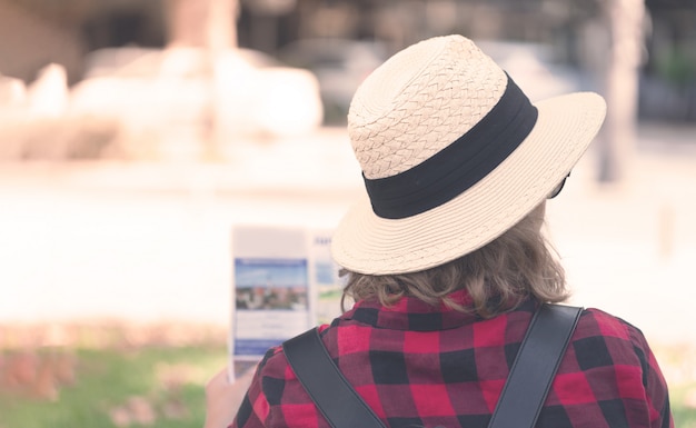 A young woman with a backpack reading a map