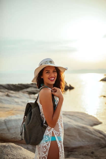 Giovane donna con uno zaino in piedi sulla spiaggia