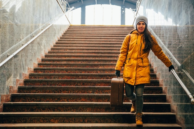 Young woman with bags on stairs at railway station