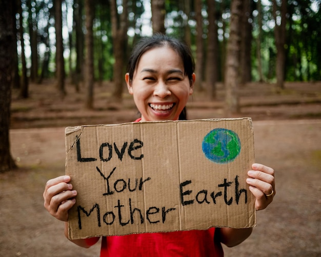 Foto giovane donna con striscioni che protesta contro l'inquinamento e il riscaldamento globale nella foresta per salvare la terra