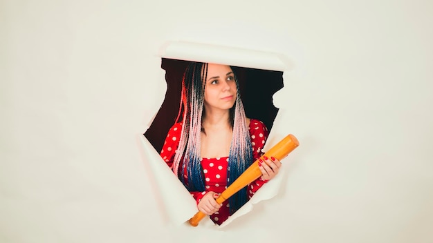 young woman with baseball bat in hole of white background pretty lady with bat